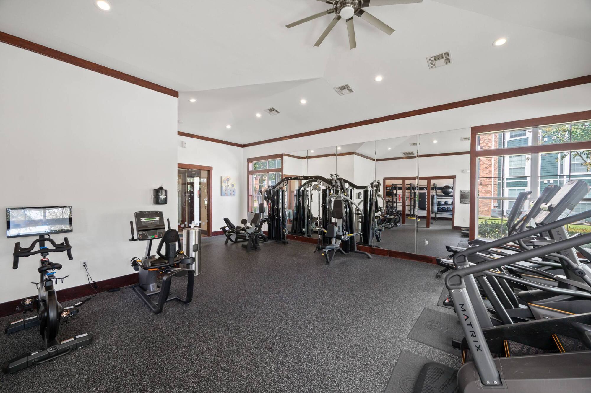 Coles Crossing fitness center with weight machines, mirrored walls, and cardio equipment in Cypress, Texas.