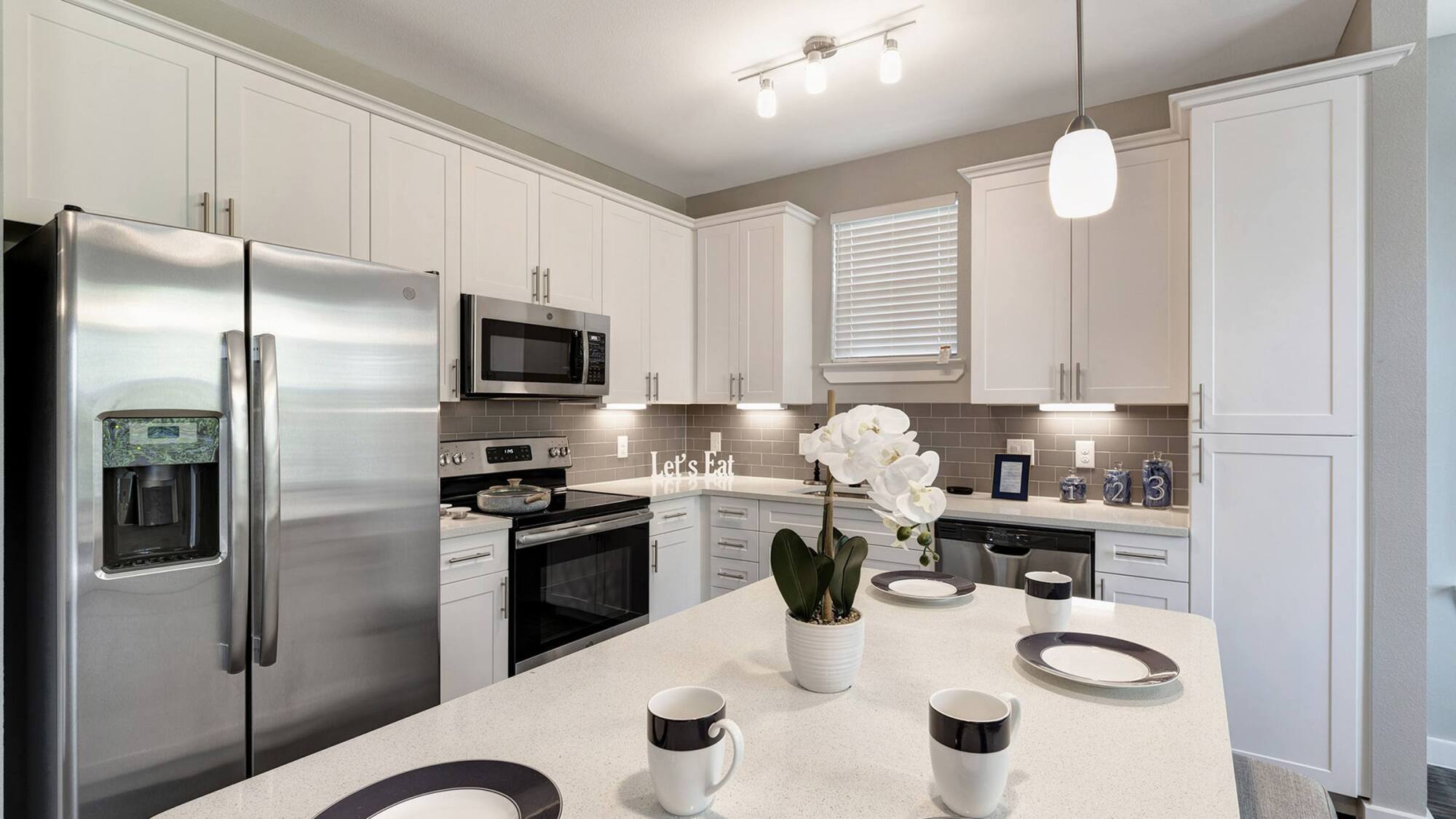 Coles Crossing apartment kitchen with white shaker cabinets, quartz countertops, and stainless steel appliances in Cypress, Texas.