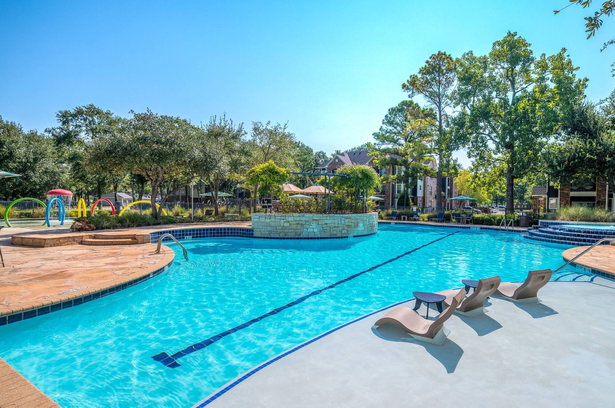 Coles Crossing resort-style swimming pool in Cypress, Texas with in-water lounge chairs and stone water features.