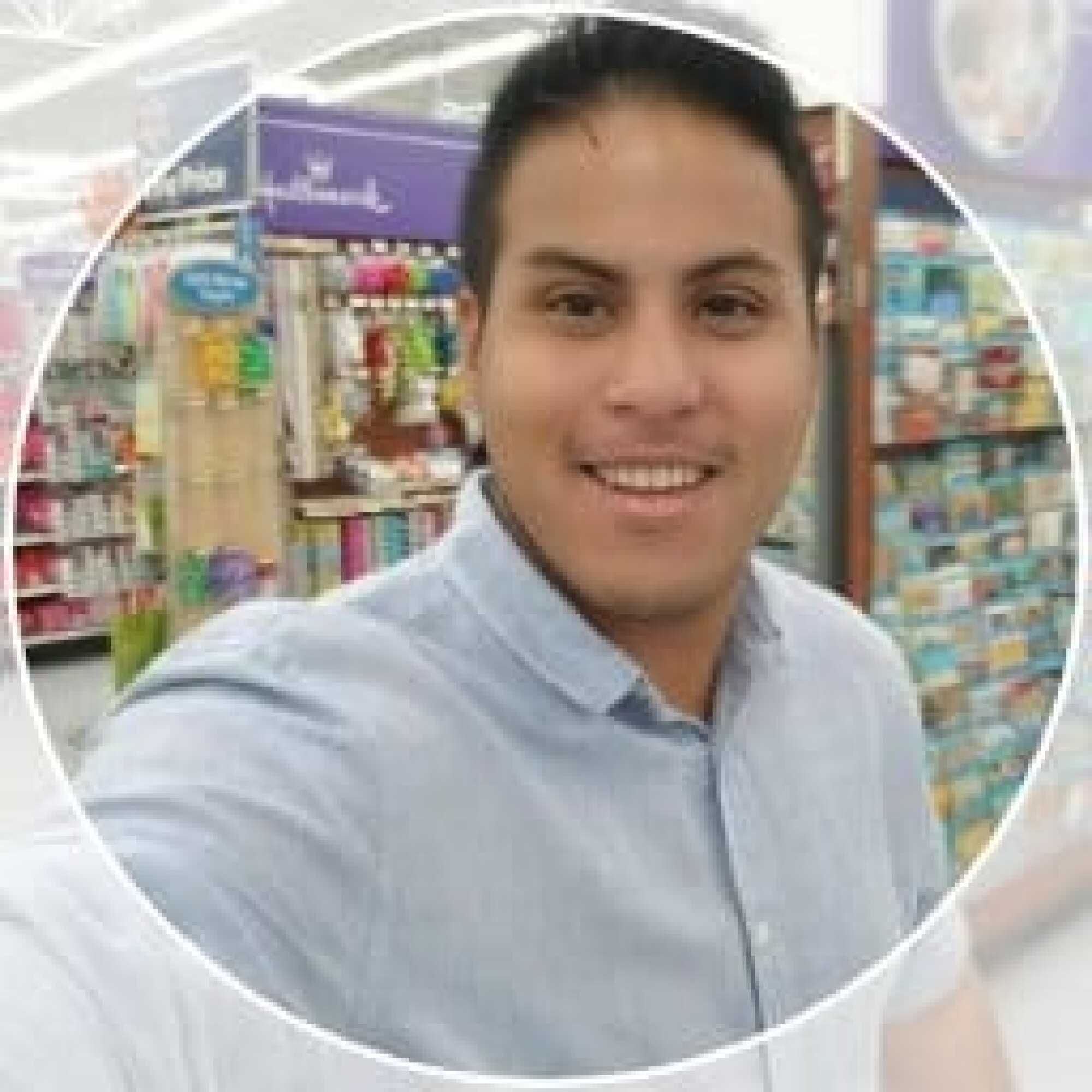 Man smiling and taking a selfie in a store aisle with shelves of products in the background.
