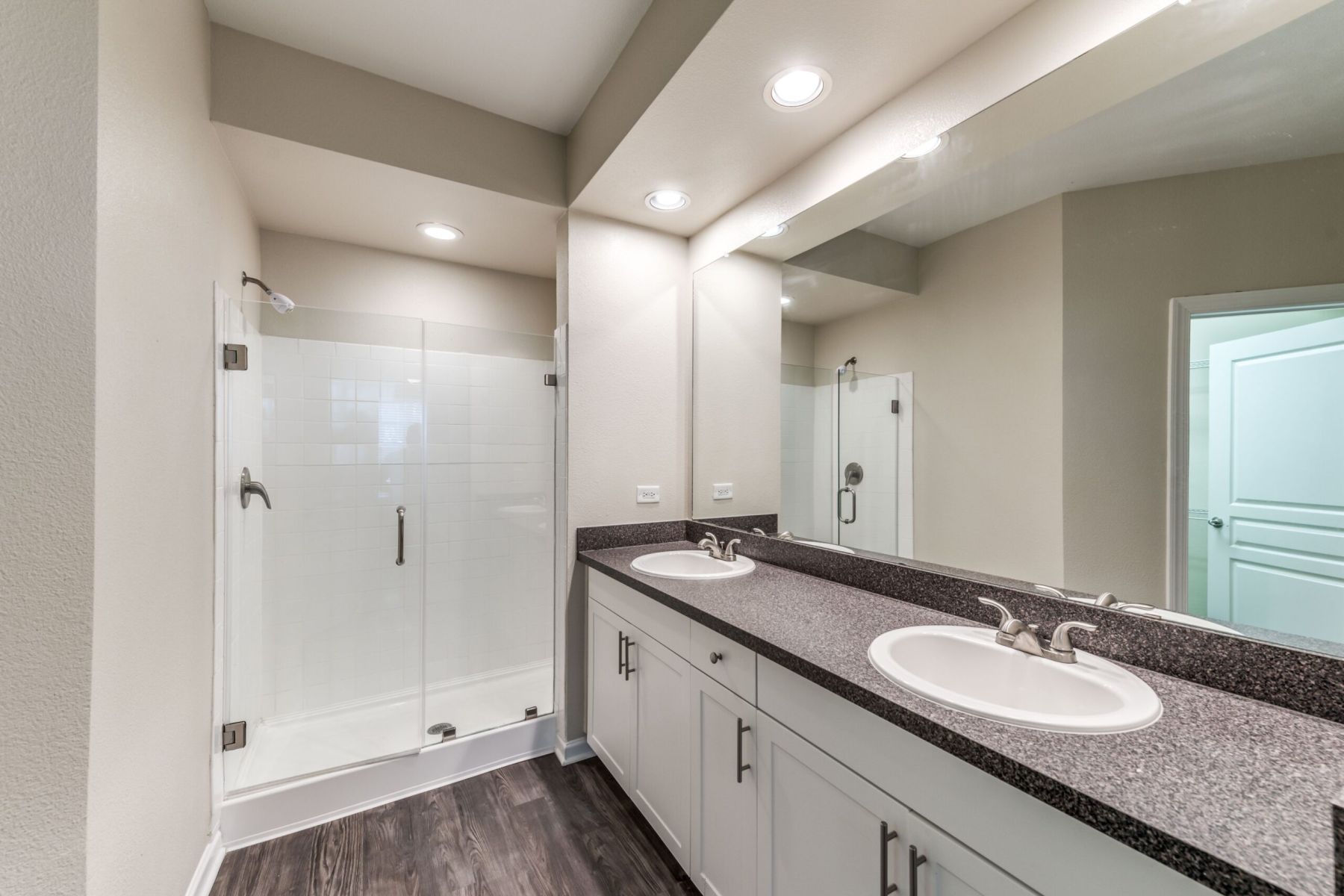 Empty room with wood floors, ceiling fan, and sliding glass door leading to a patio with vertical blinds at Apex West Midown.